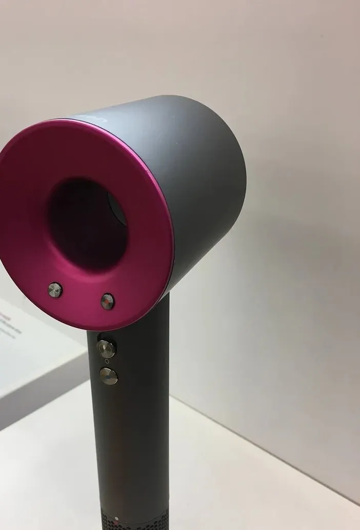 A Dyson Supersonic hair dryer on a white retail stand