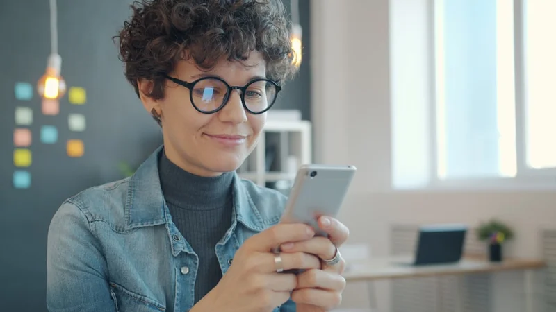 Photographer checking SMS messages and email on phone — the two-channel follow-up system