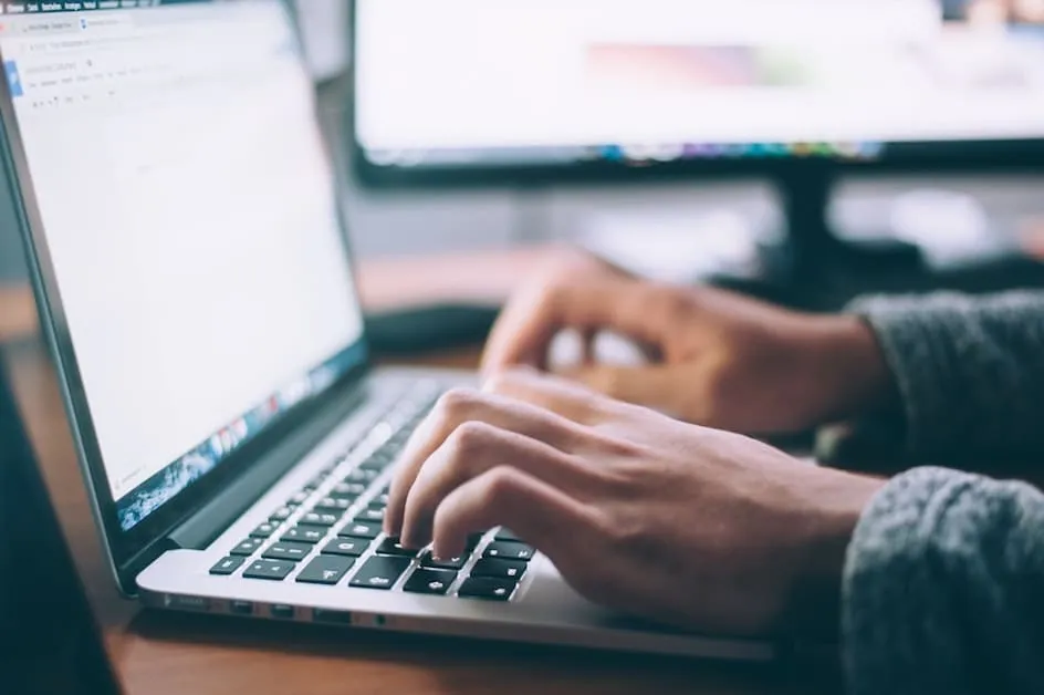 Person Typing On An Open Laptop