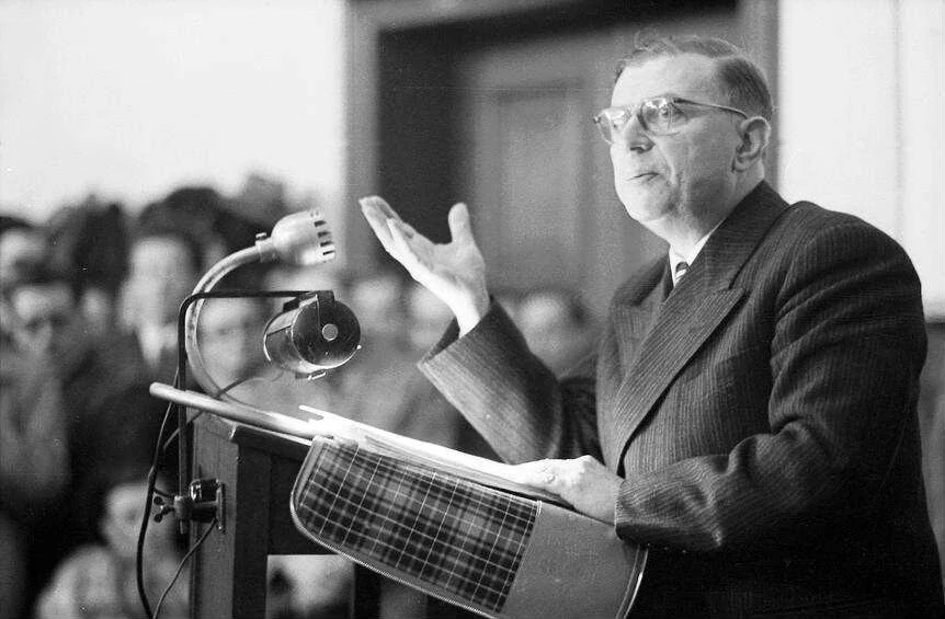 Jean-Paul Sartre speaking at a lectern at the University of Freiburg in 1953